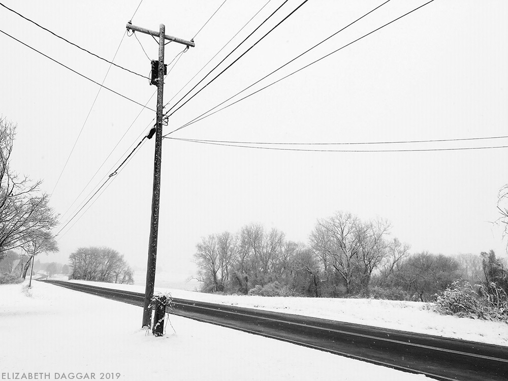 telephone pole and wires in snow (b&w photo)