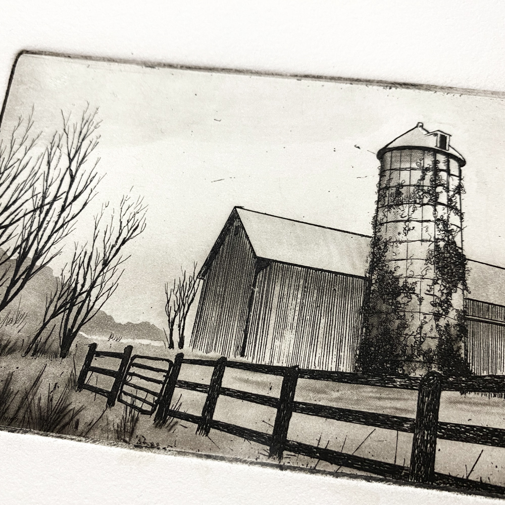 Close up of an print of a barn and silo, made with line etch and aquatint on a copper plate